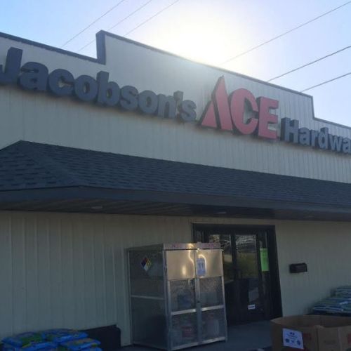 Jacobson's Ace Hardware storefront features a metal roof, a large sign, and various supplies stacked outside. - Rice Lake Chamber of Commerce